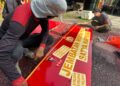 Personel Batalyon D Pelopor Memasang Stiker Plank Nama Jembatan Salusule