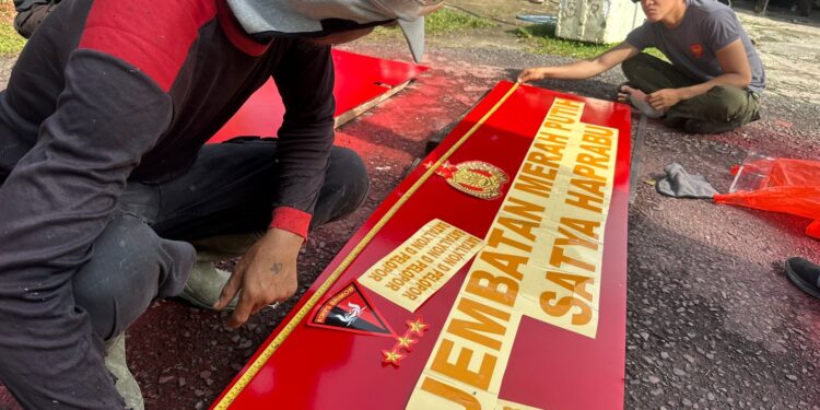 Personel Batalyon D Pelopor Memasang Stiker Plank Nama Jembatan Salusule